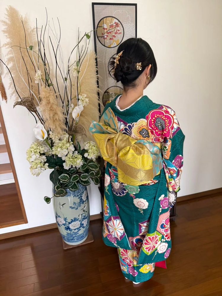 深緑地に華やかな花柄の振袖の帯結び（後ろ姿）
